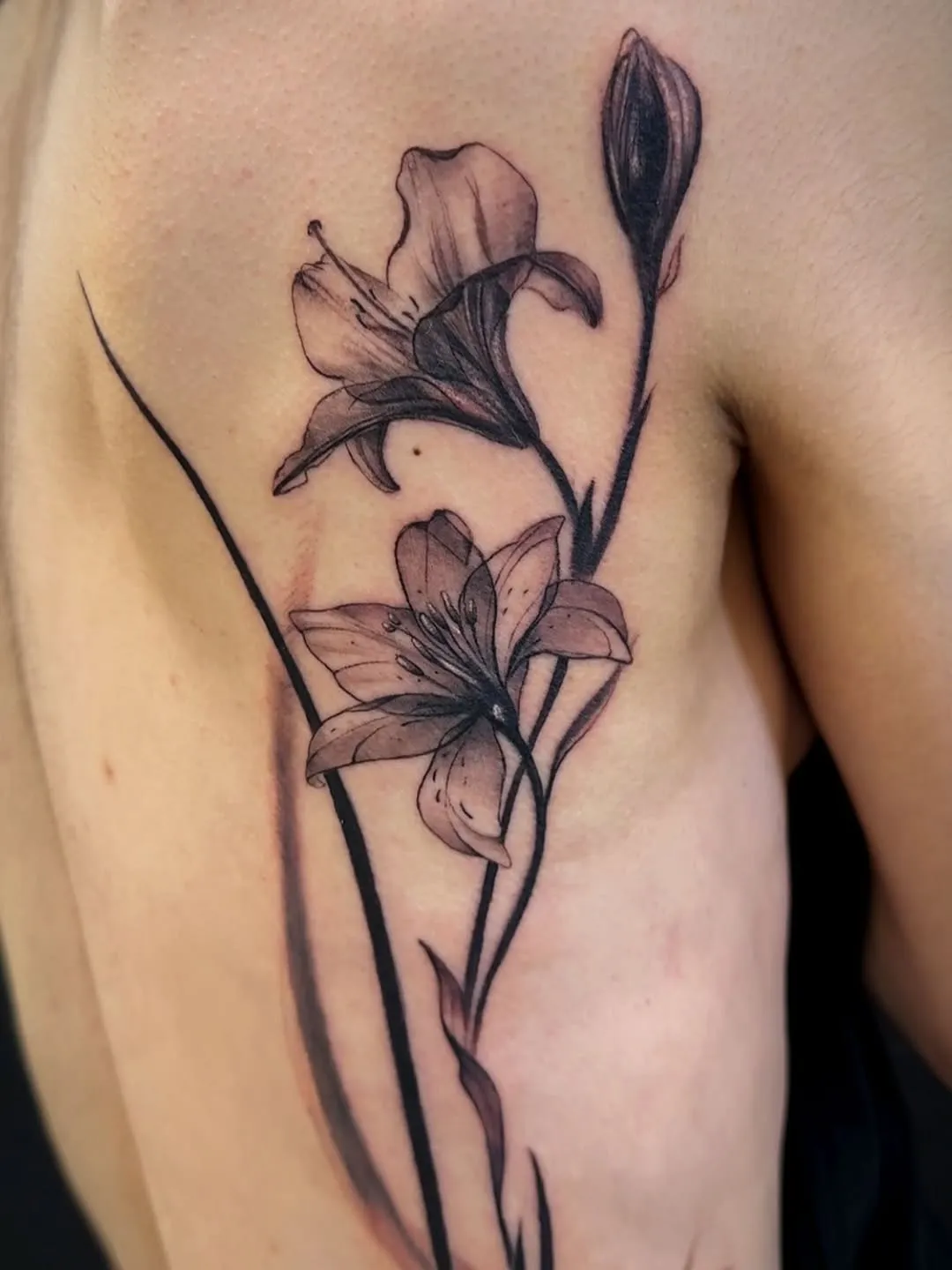 Black and grey lily flower ribcage tattoo by Joan Martinez at Studio AZ Tattoo Minneapolis