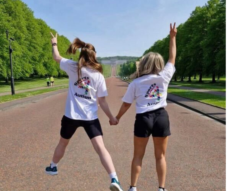 Two Sports 4 Autism coaches walking hand-in-hand along the tree-lined path toward Stormont