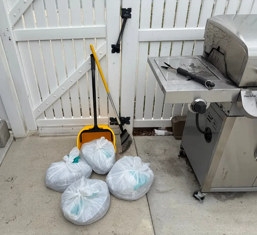 Tied collection bags and tools after a Waggin Waste yard cleanup