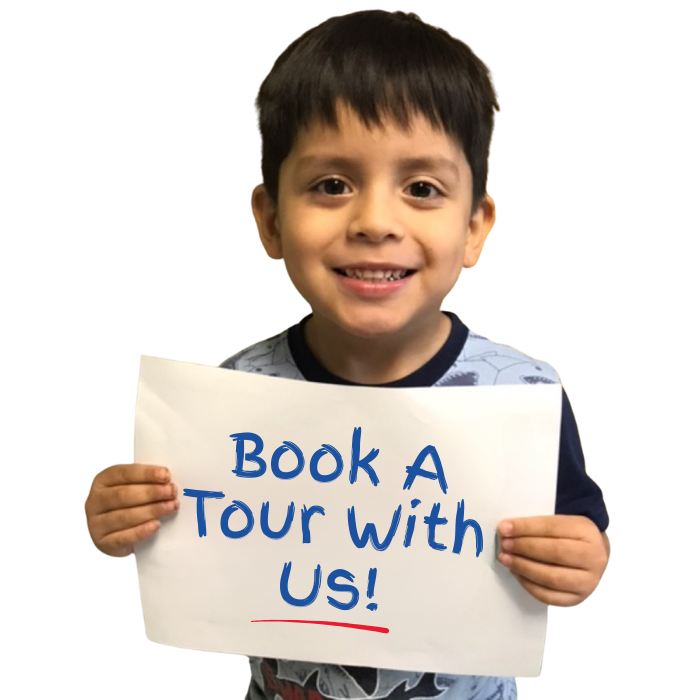 Smiling child holding Book a Tour sign at Magic Kingdom Learning Center childcare and preschool in Harlingen TX