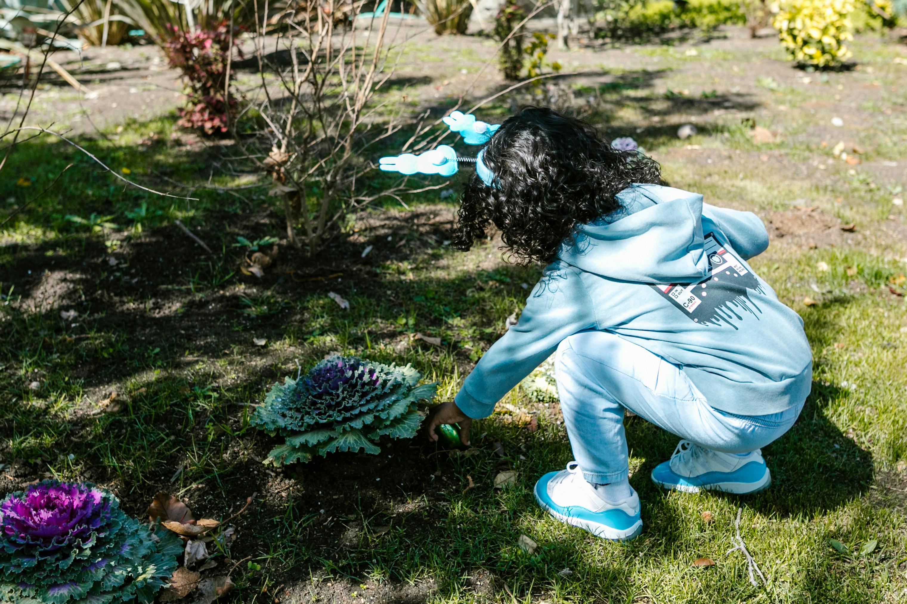 An image of a young girl exploring different flowers and plants outdoors An image of a young girl exploring different flowers and plants outdoors