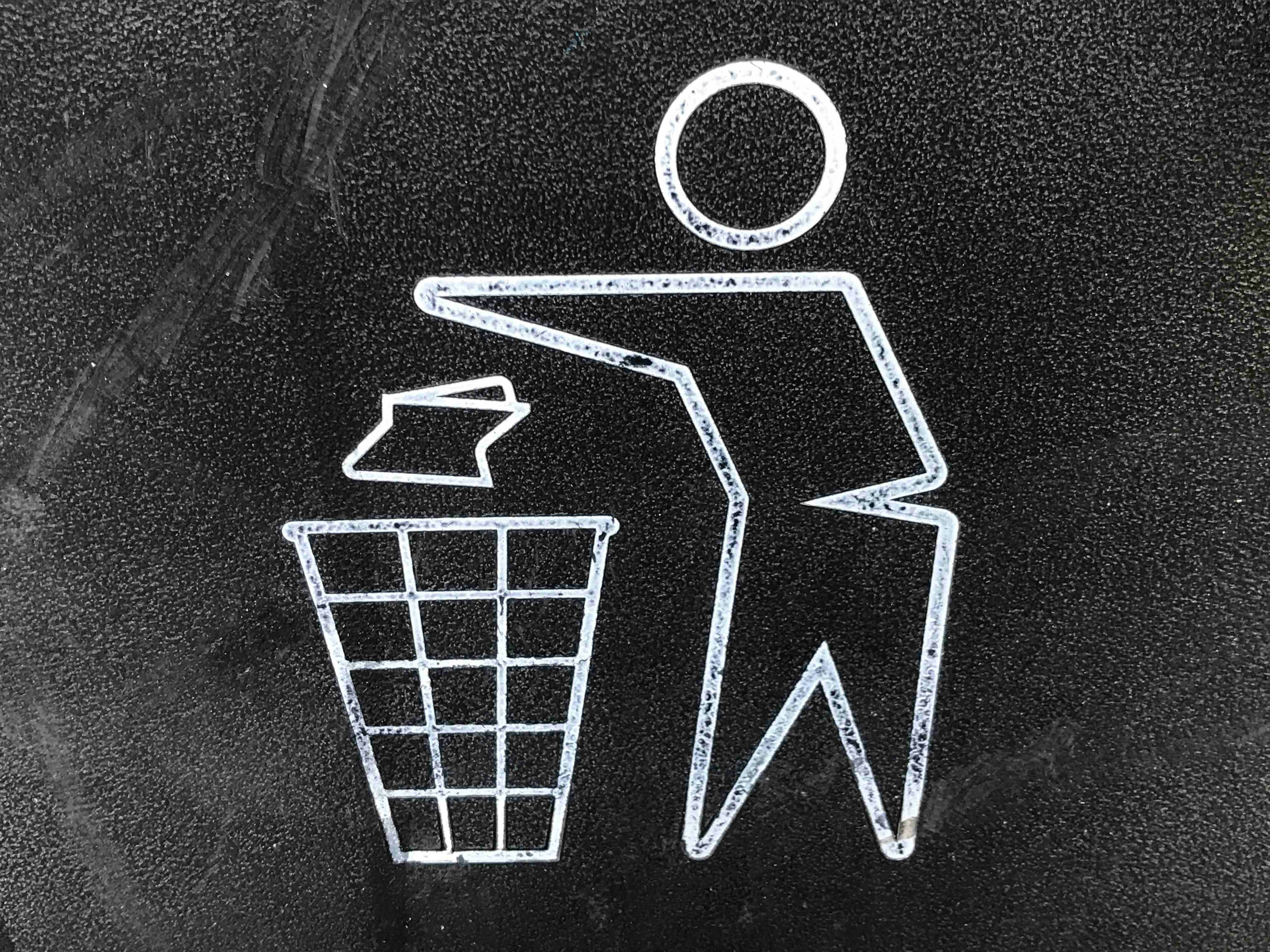 An image of a white outline character dropping some rubbish in a bin on a black background