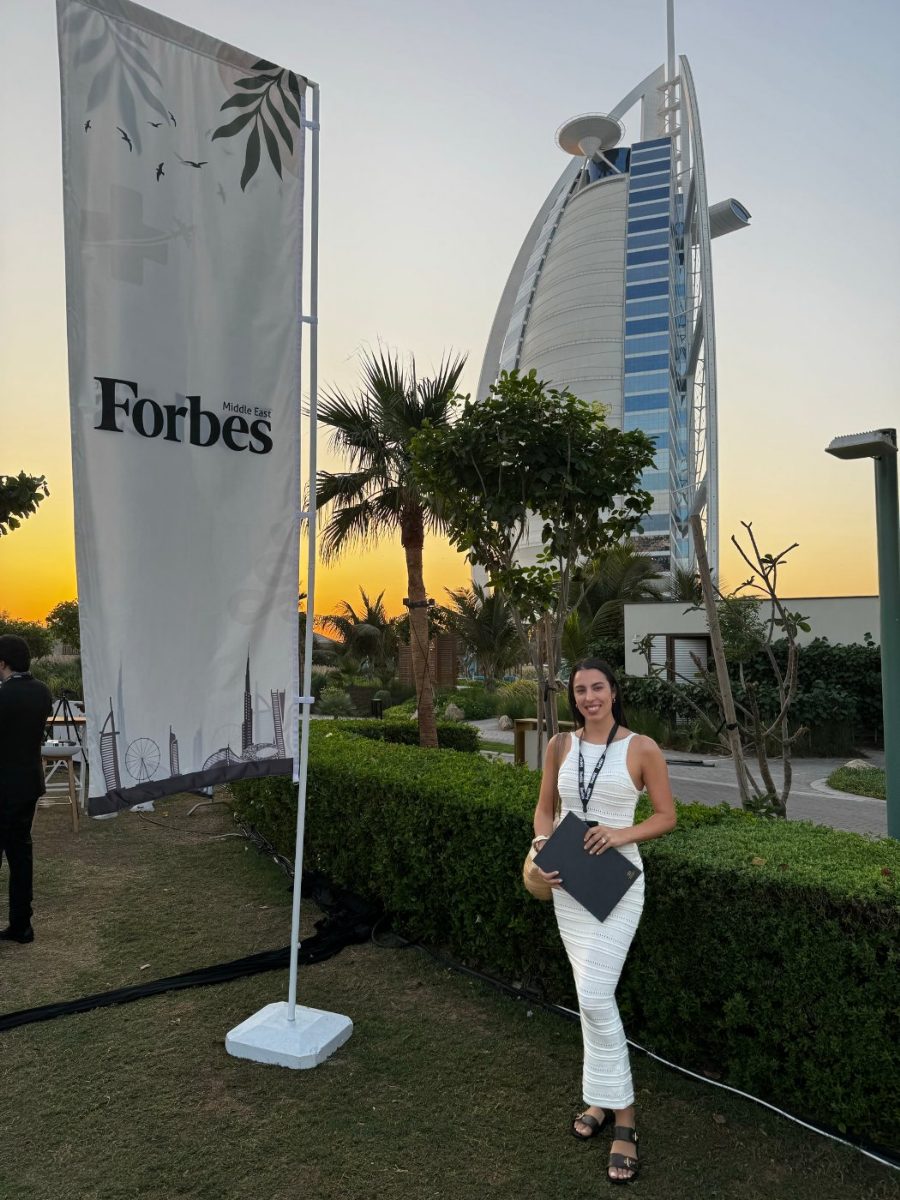 Erika beside a Forbes flag with the Burj Al Arab behind