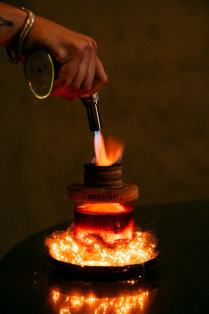A bartender torching Kaya's smoked old fashioned
