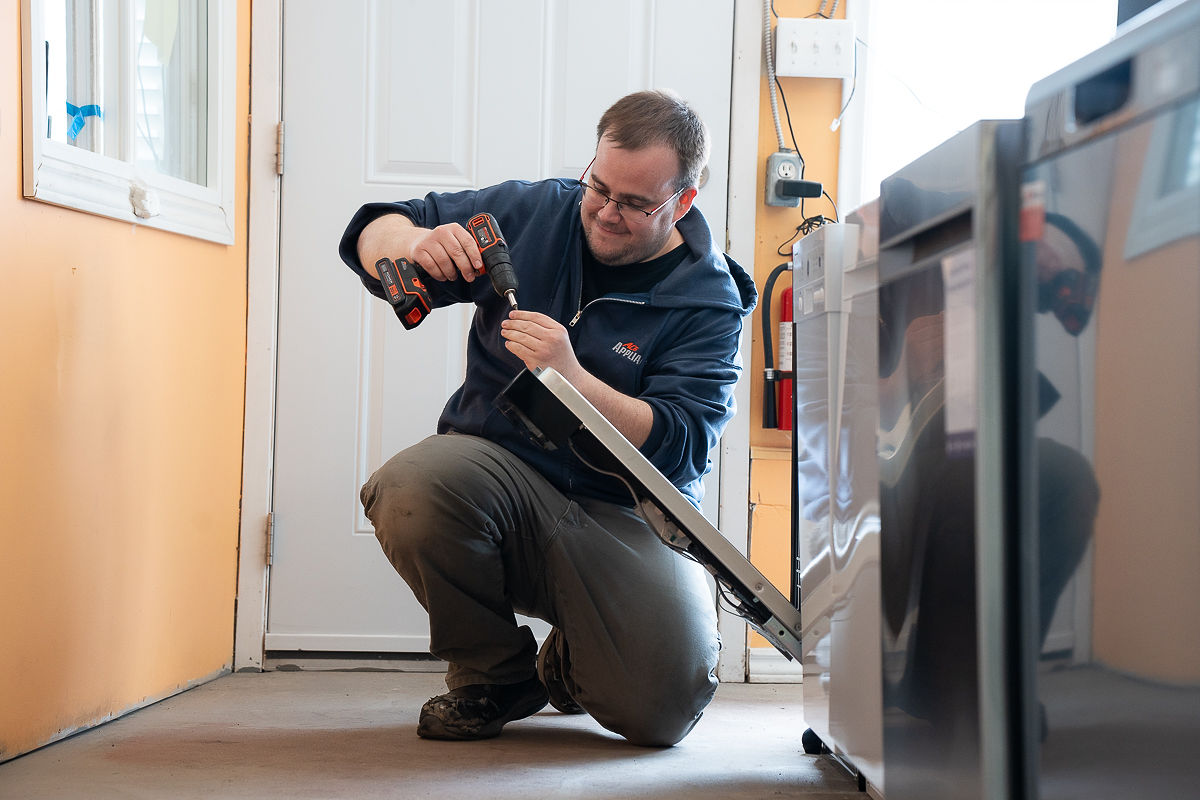 Al's Appliance technician repairing a refrigerator ice maker