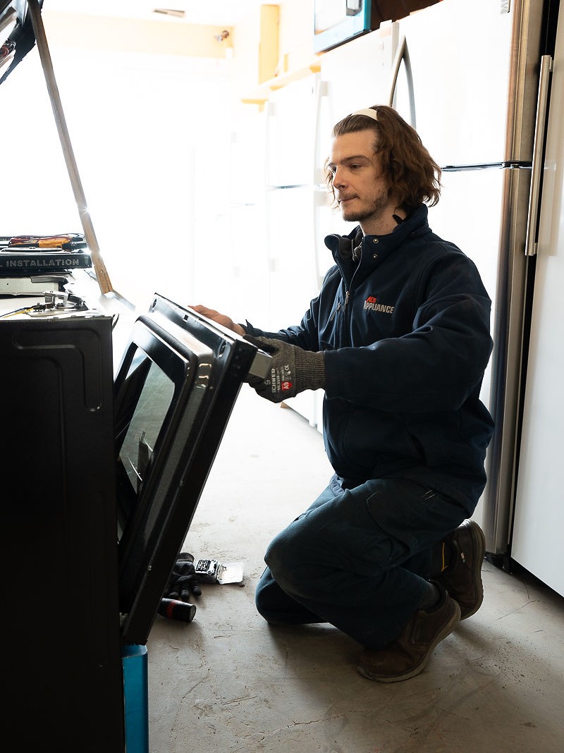 Al's Appliance technician inspecting an oven door during a spring appliance maintenance check