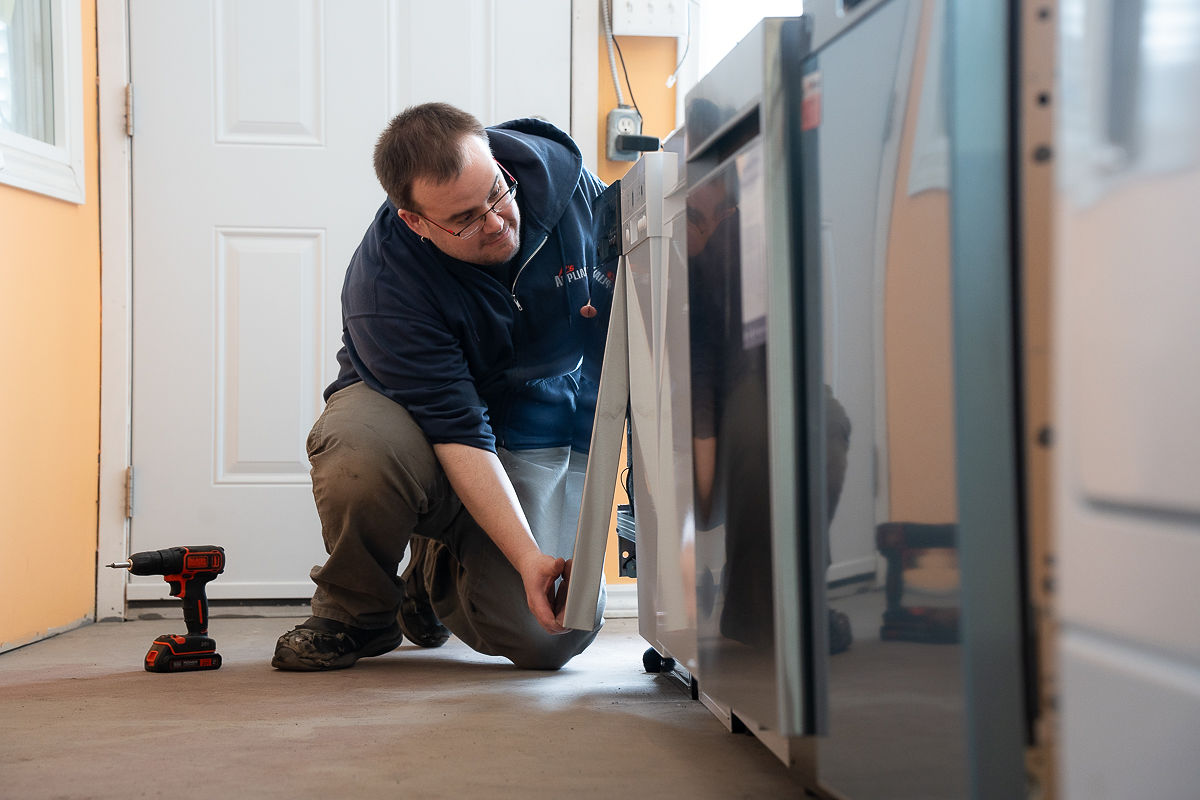Al's Appliance technician servicing a stainless steel refrigerator that is not cooling