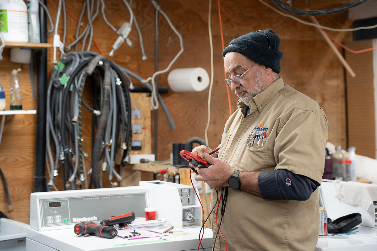 Al's Appliance technician testing appliance parts with a multimeter to decide between repair and replacement