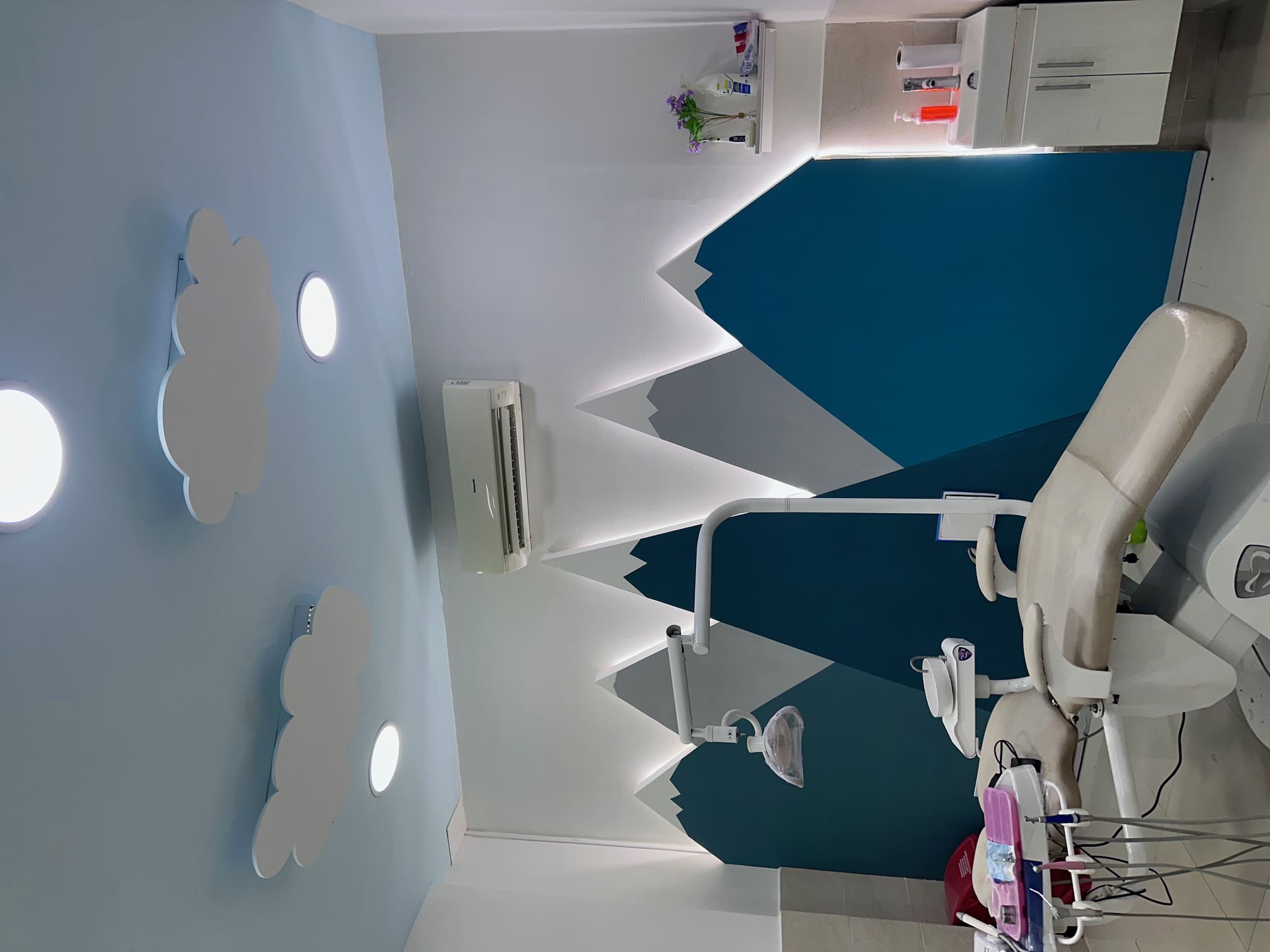 Consultorio dental con sillón y mural de montañas azules y nubes en el techo en Santa Marta