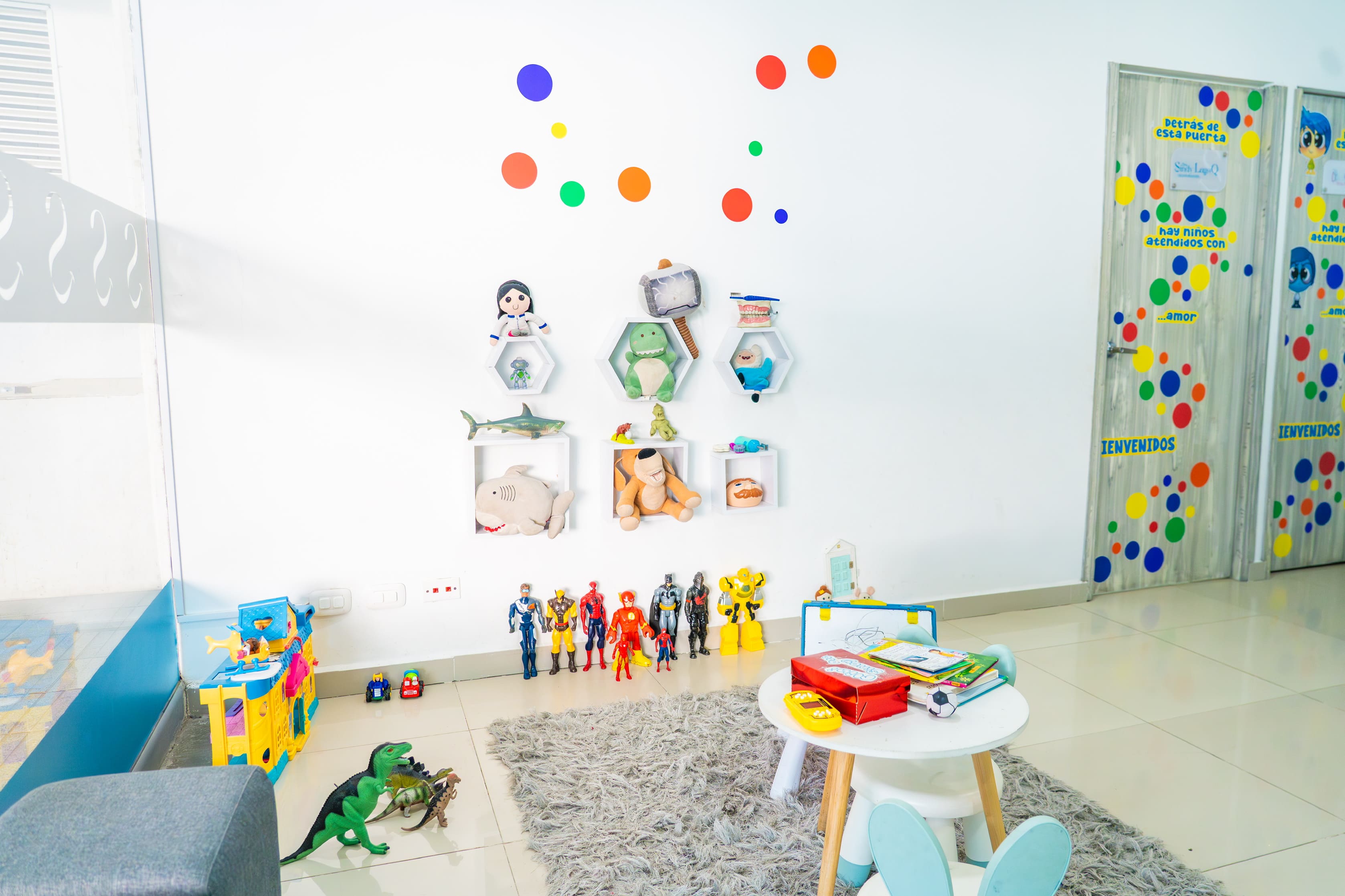 Rincón de juegos del consultorio de odontopediatría con estantes hexagonales de peluches y figuras de acción, en Santa Marta