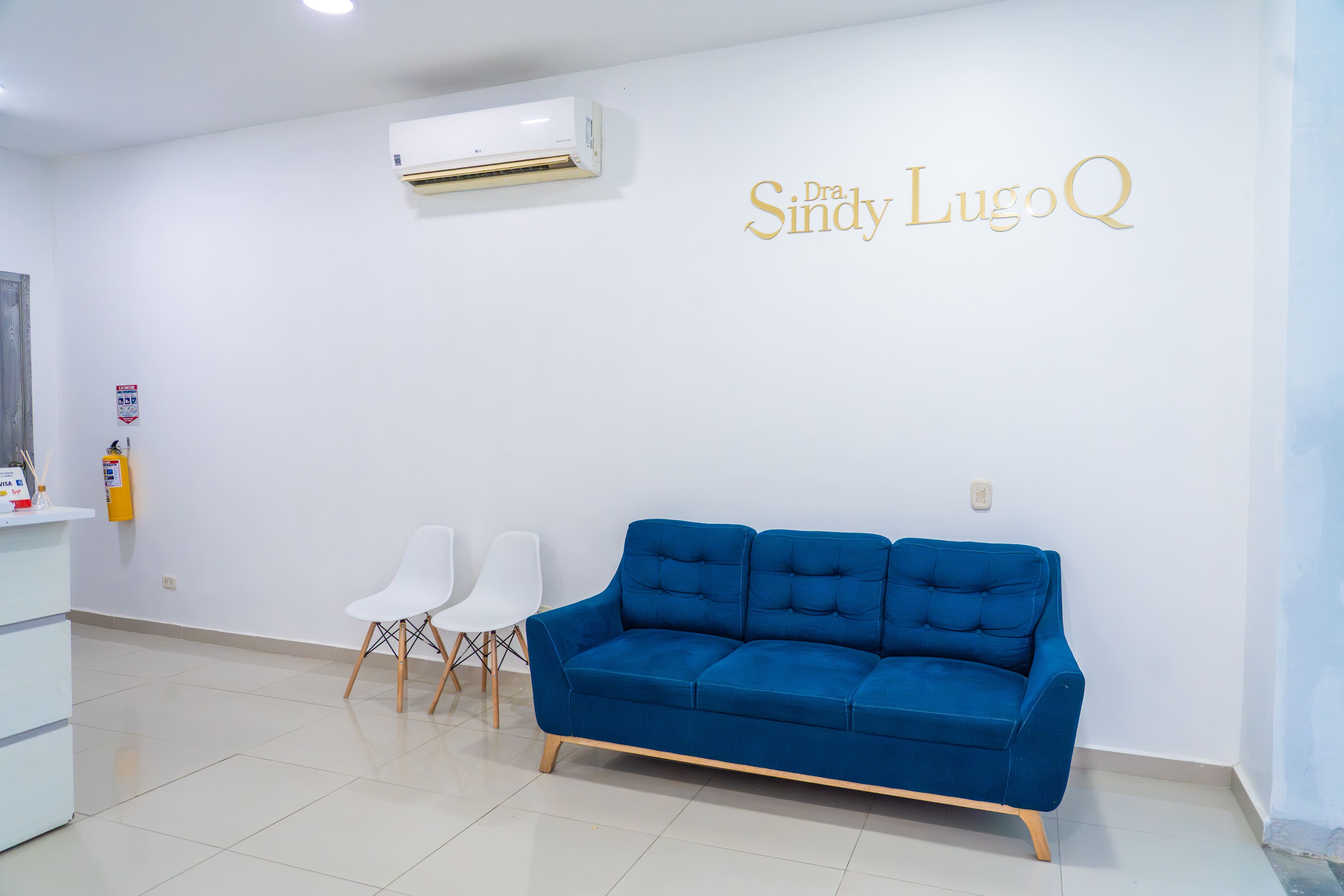 Sala de espera con sofá azul y letras doradas del nombre del consultorio en la pared, en Santa Marta