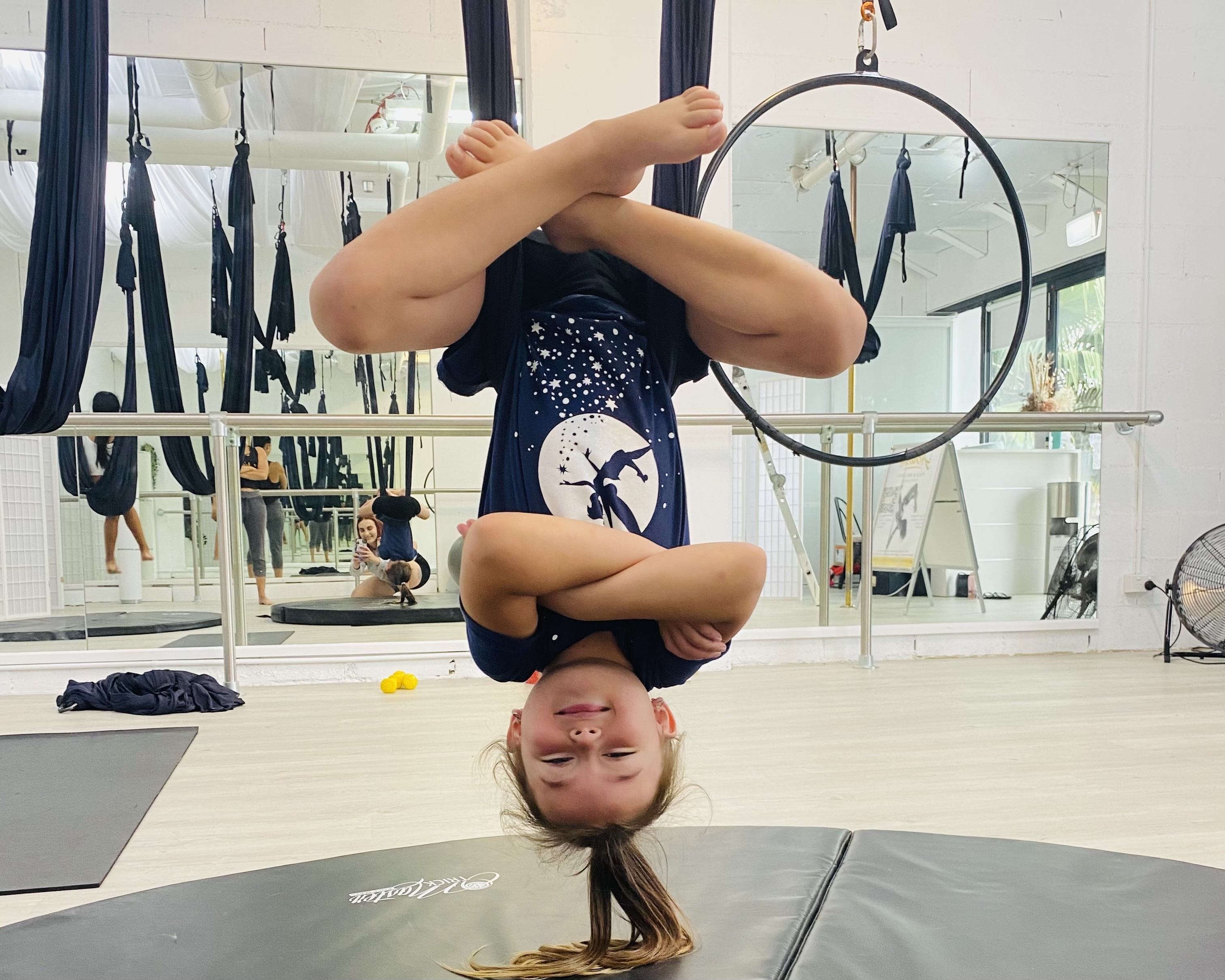 Coach helping a child stretch at Achieve Pole Studio