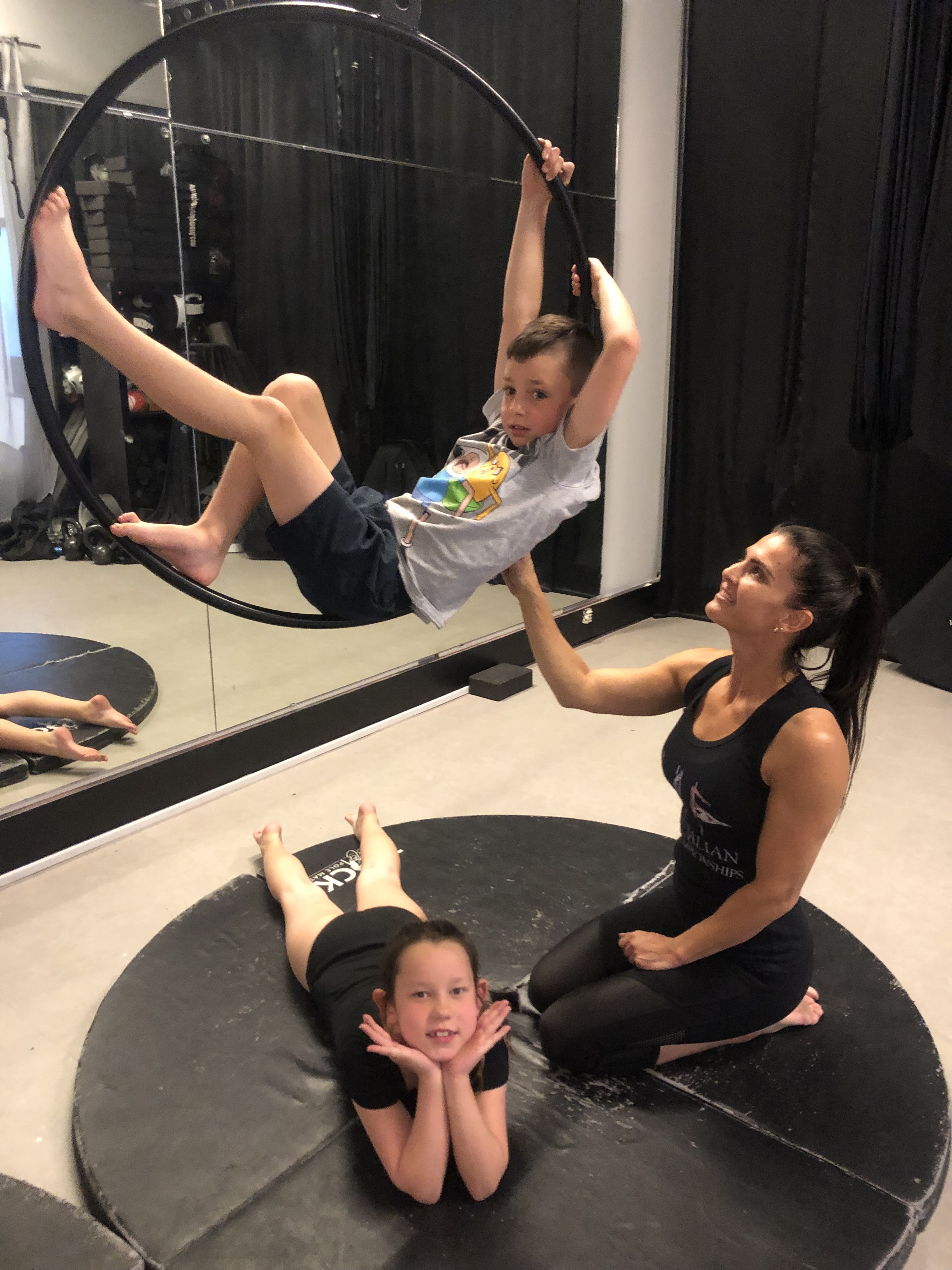 Coach helping a child on Aerial Hoop at Achieve Pole Studio