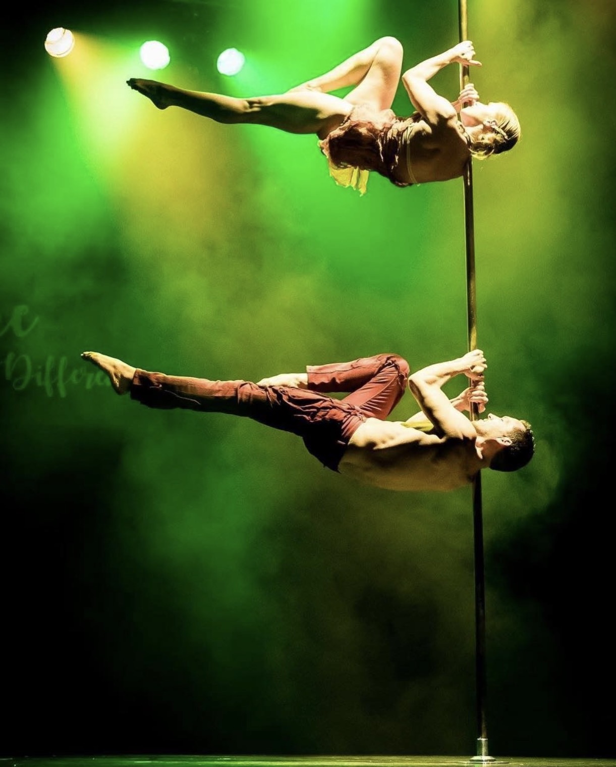 Toby J in a doubles pole performance under green stage lights