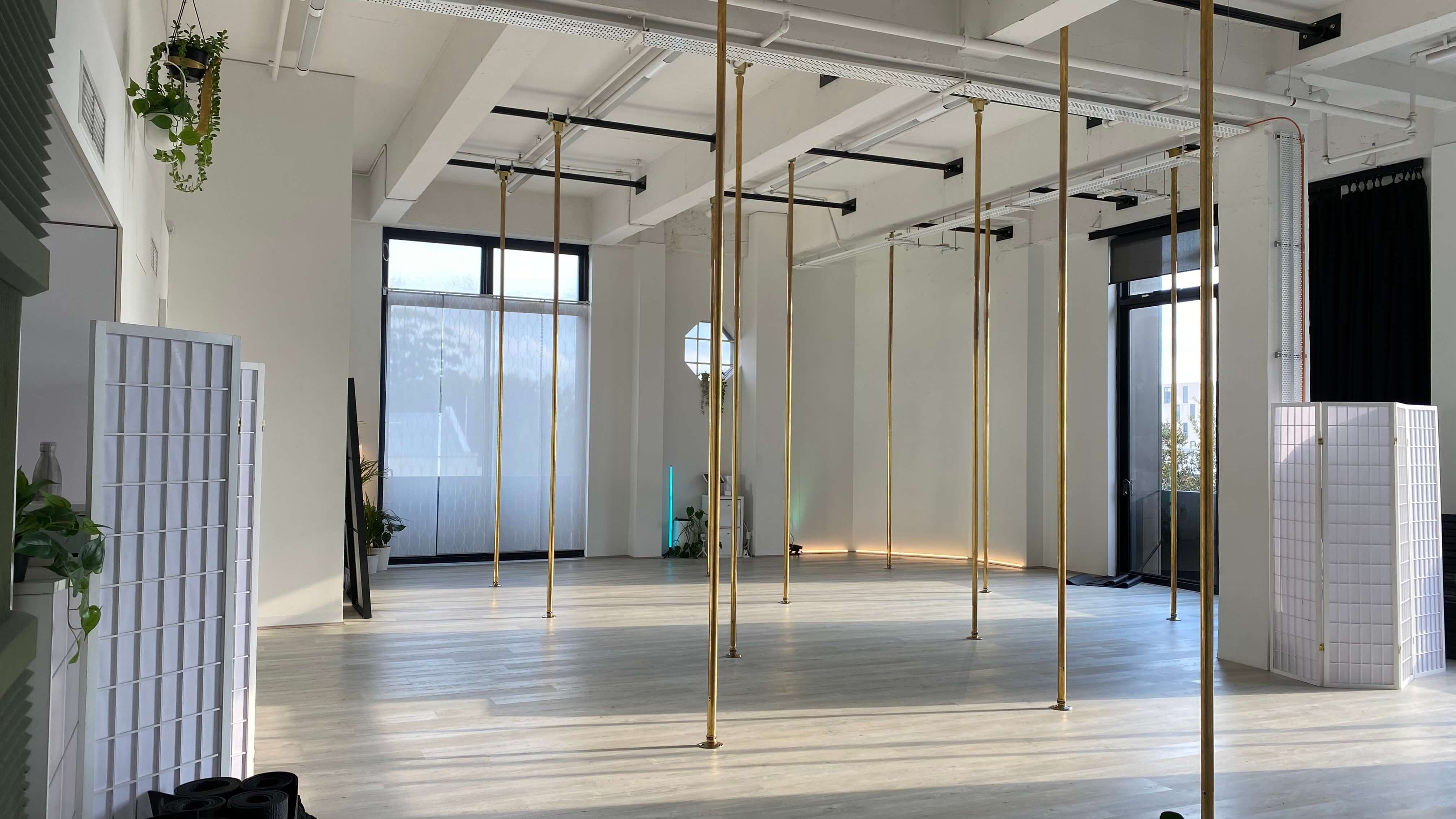 Achieve Pole Studio, bright and empty with gold poles