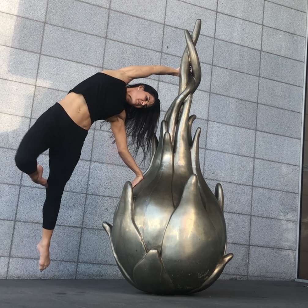 Andrea Ryff in a dance pose beside a bronze sculpture