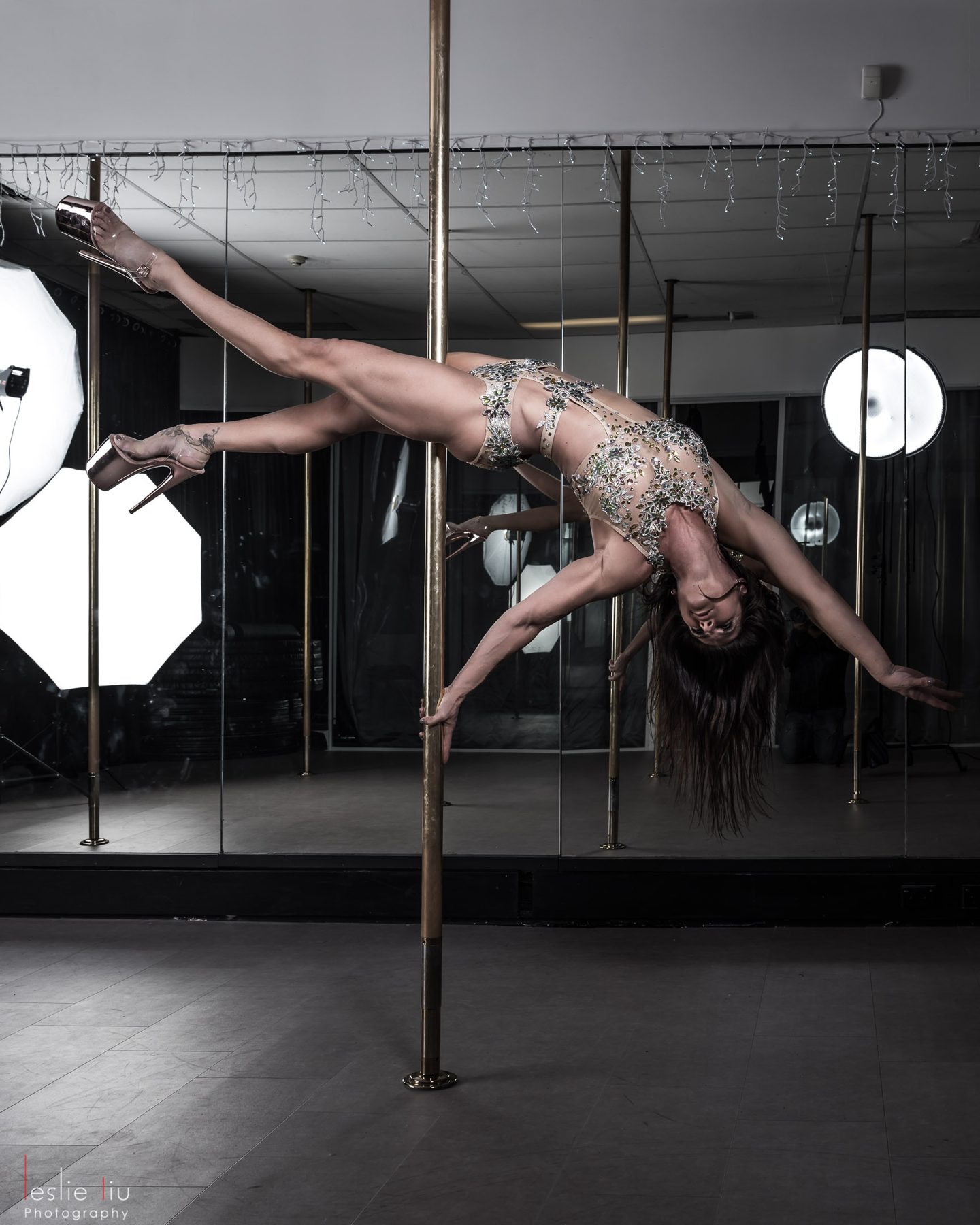 Andrea Ryff in a horizontal pole hold in a mirrored studio