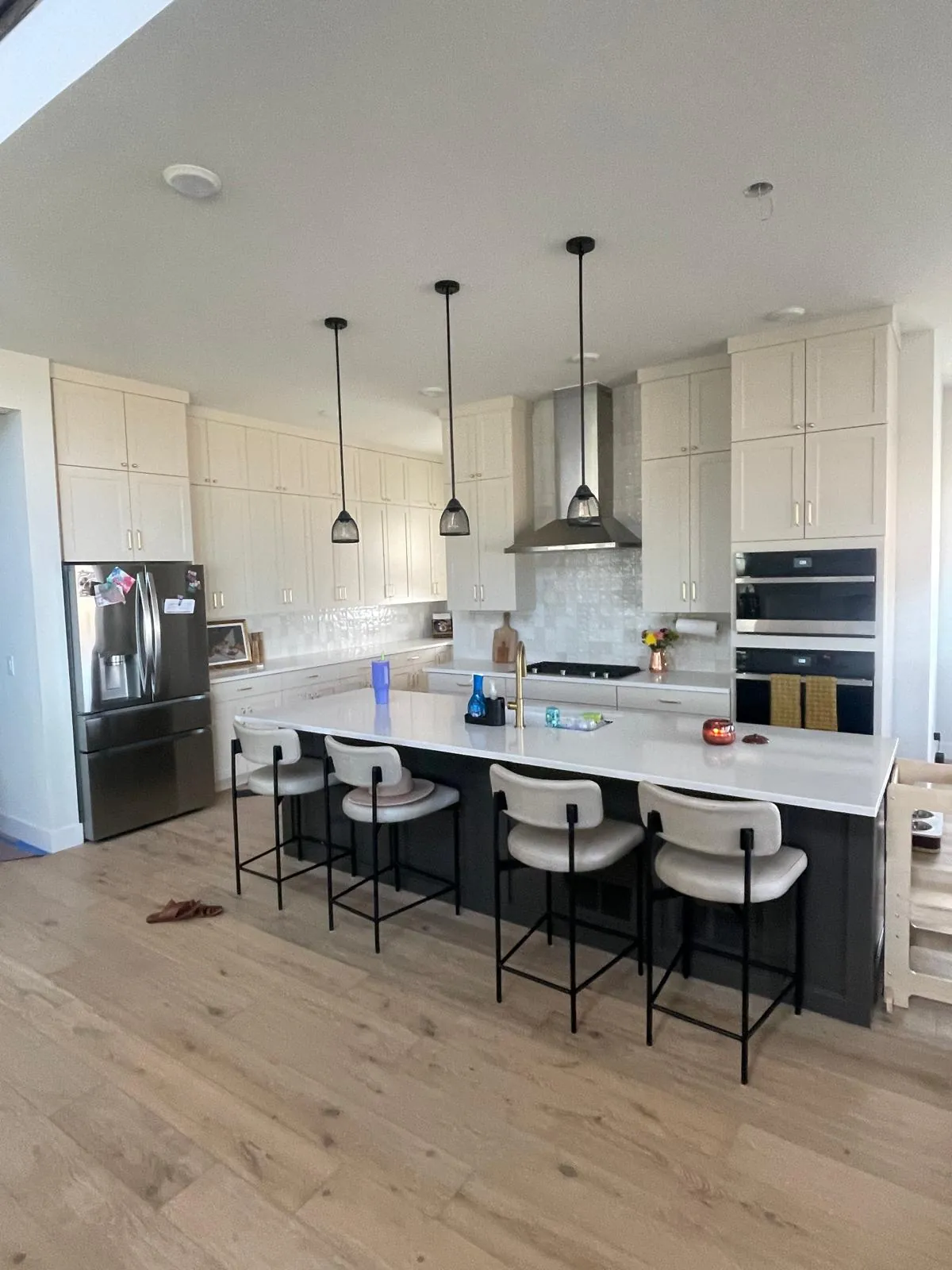 Finished kitchen with white island, pendant lights, range hood and bar stools
