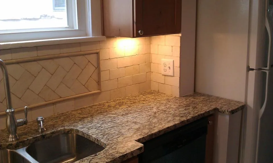 Kitchen corner with tile backsplash, granite countertop and stainless fridge