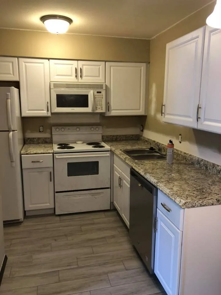 White kitchen with granite counters, range, microwave and dishwasher installed