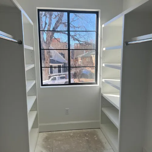 Built-in white shelving installed around a black-framed window