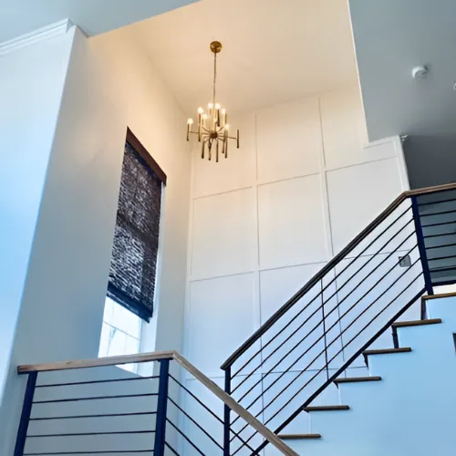 Remodeled stairwell with a modern black railing and pendant chandelier