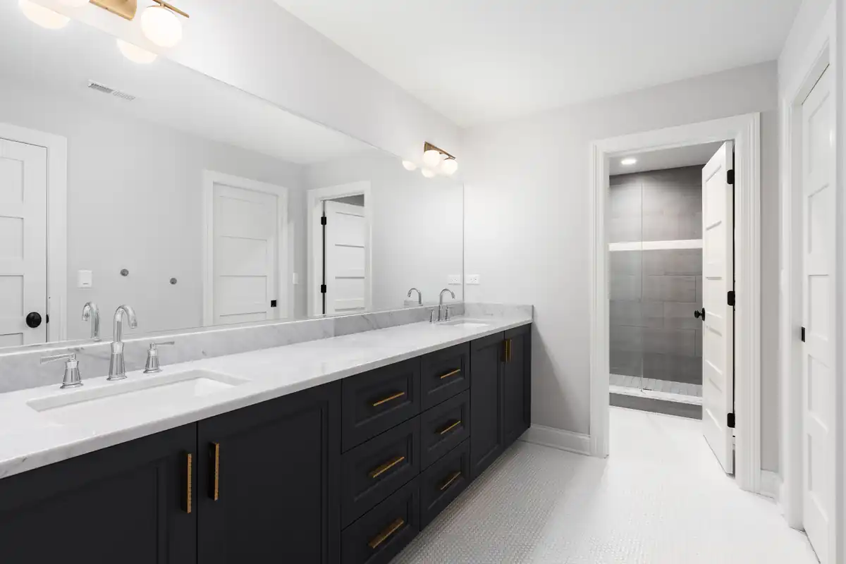 Bathroom double vanity with dark base cabinets installed beneath a full-width mirror