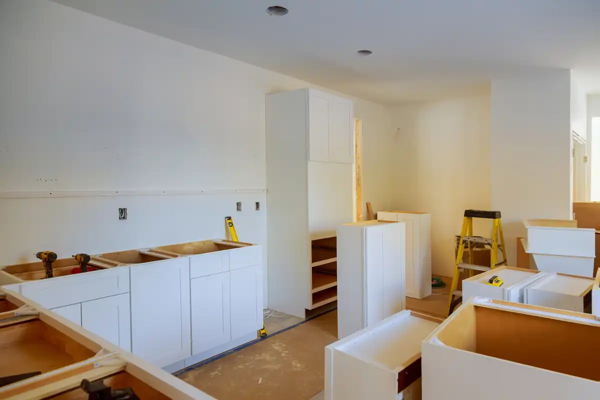 White cabinet run being installed with boxes and a step ladder still in the room