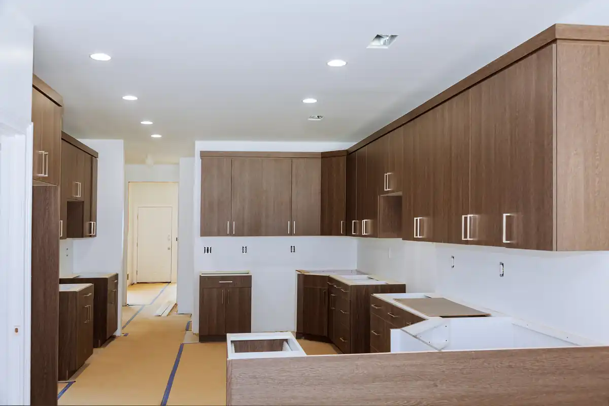 Kitchen part-way through cabinet installation with wood upper cabinets and white base units