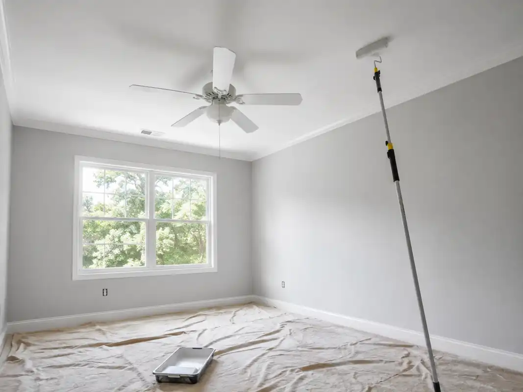 Room prepared for painting with drop cloths and an extension roller in place