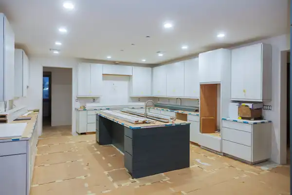 Finished white kitchen with a large island and recessed lighting after cabinet installation