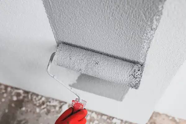 Roller applying an even coat of paint across a prepared interior wall
