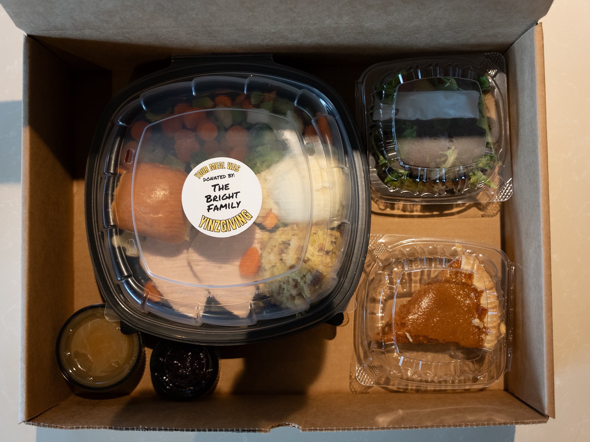 A YINZgiving meal box opened, showing the meal and the donor sticker