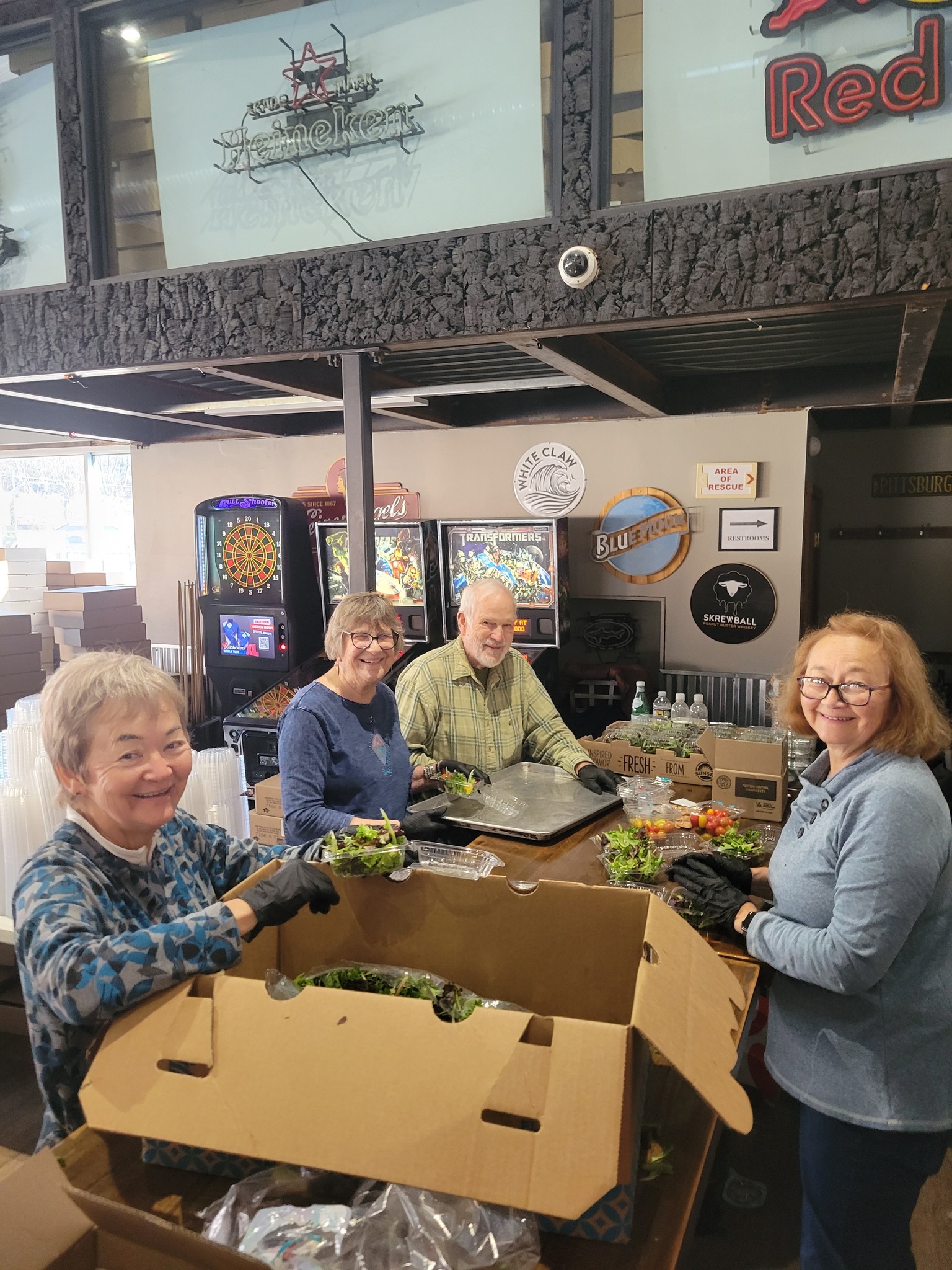 Senior volunteers packing fresh salads on prep day inside Dive Bar & Grille