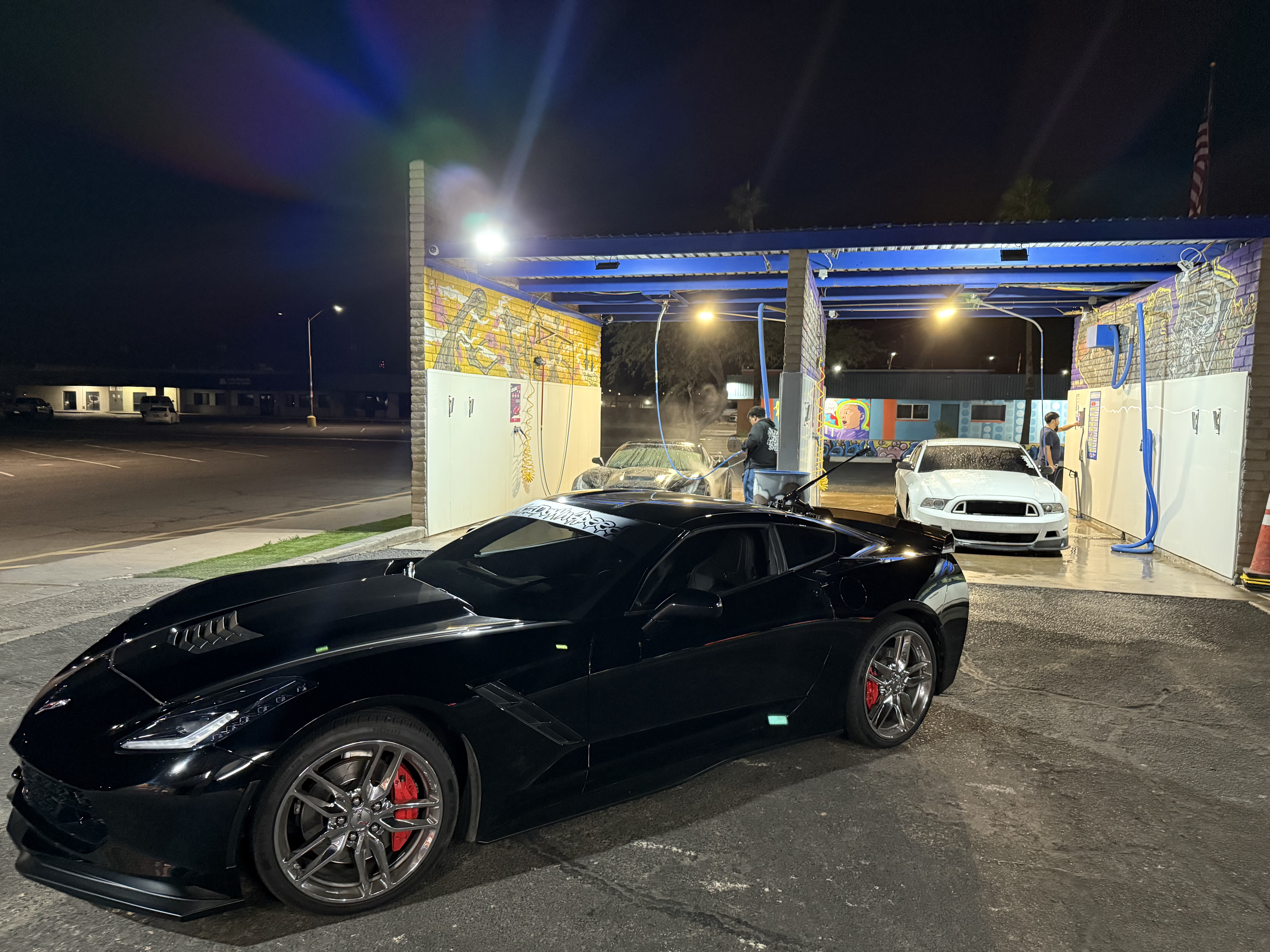 Black Corvette pulling out of a Bobby E's bay at night in Tempe