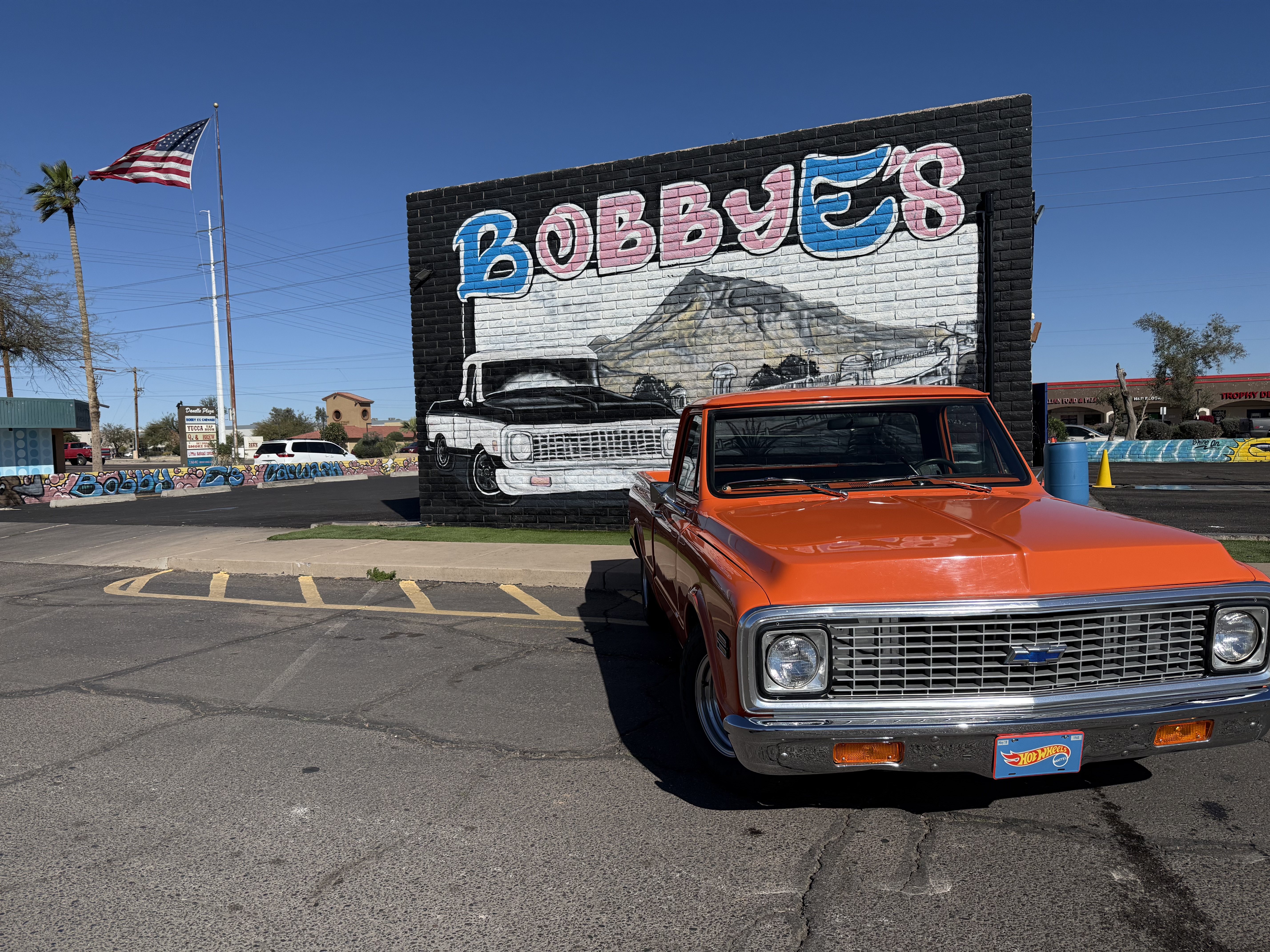 Orange classic Chevy truck in front of the Bobby E's mural on Southern Ave