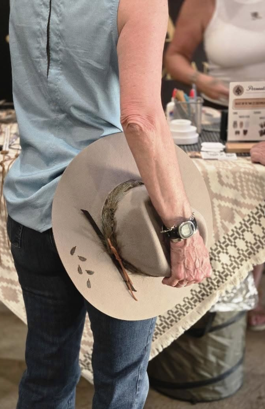 Guest holding a cream custom hat at an Ace High hat bar