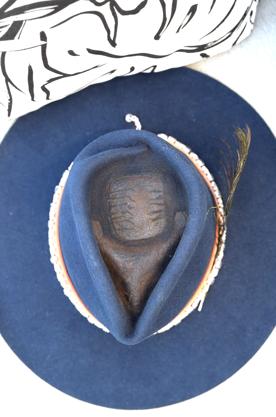 Top view of a navy felt hat with a teardrop crown