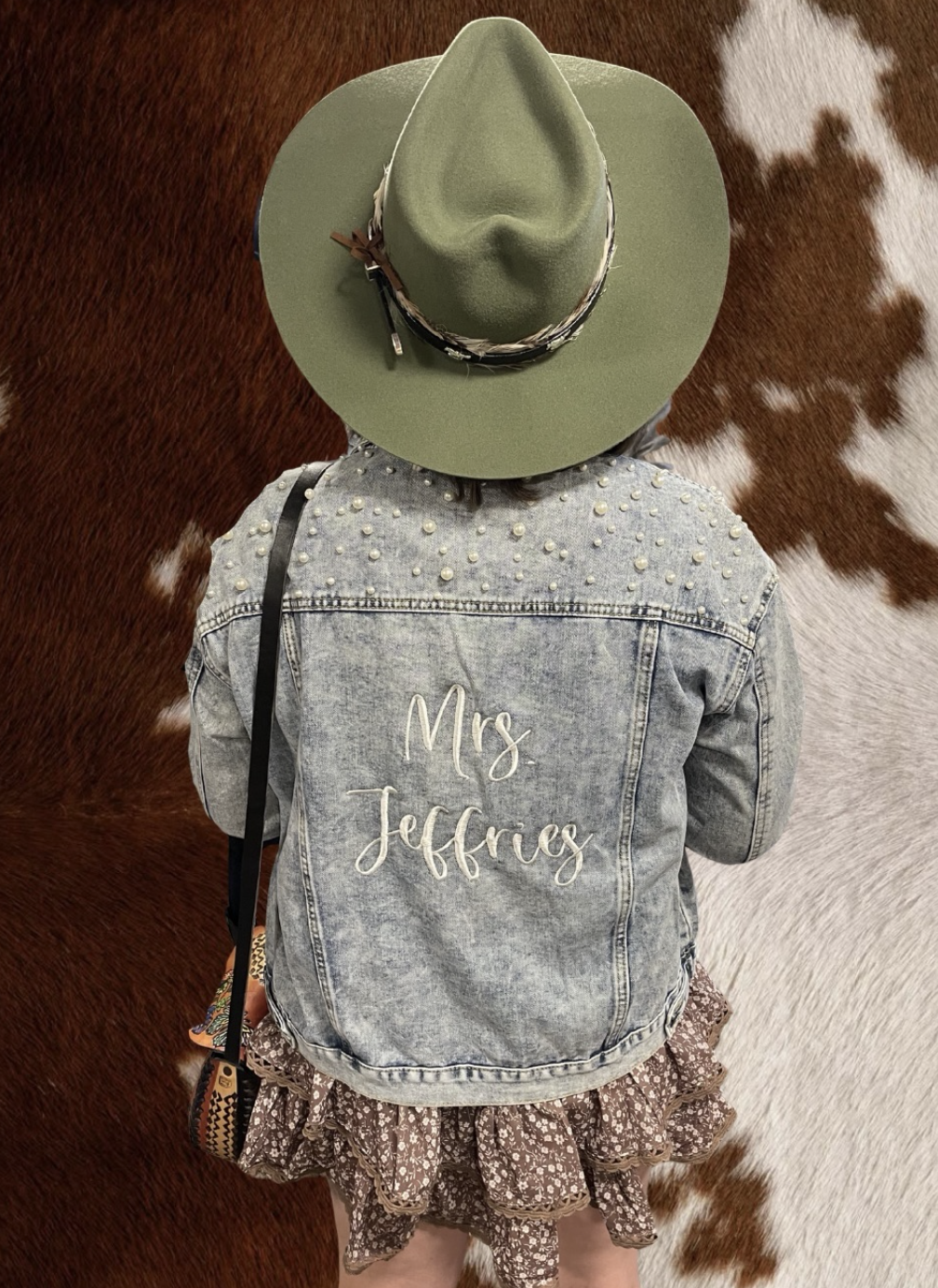 Bride-to-be in a sage felt hat and personalized denim jacket