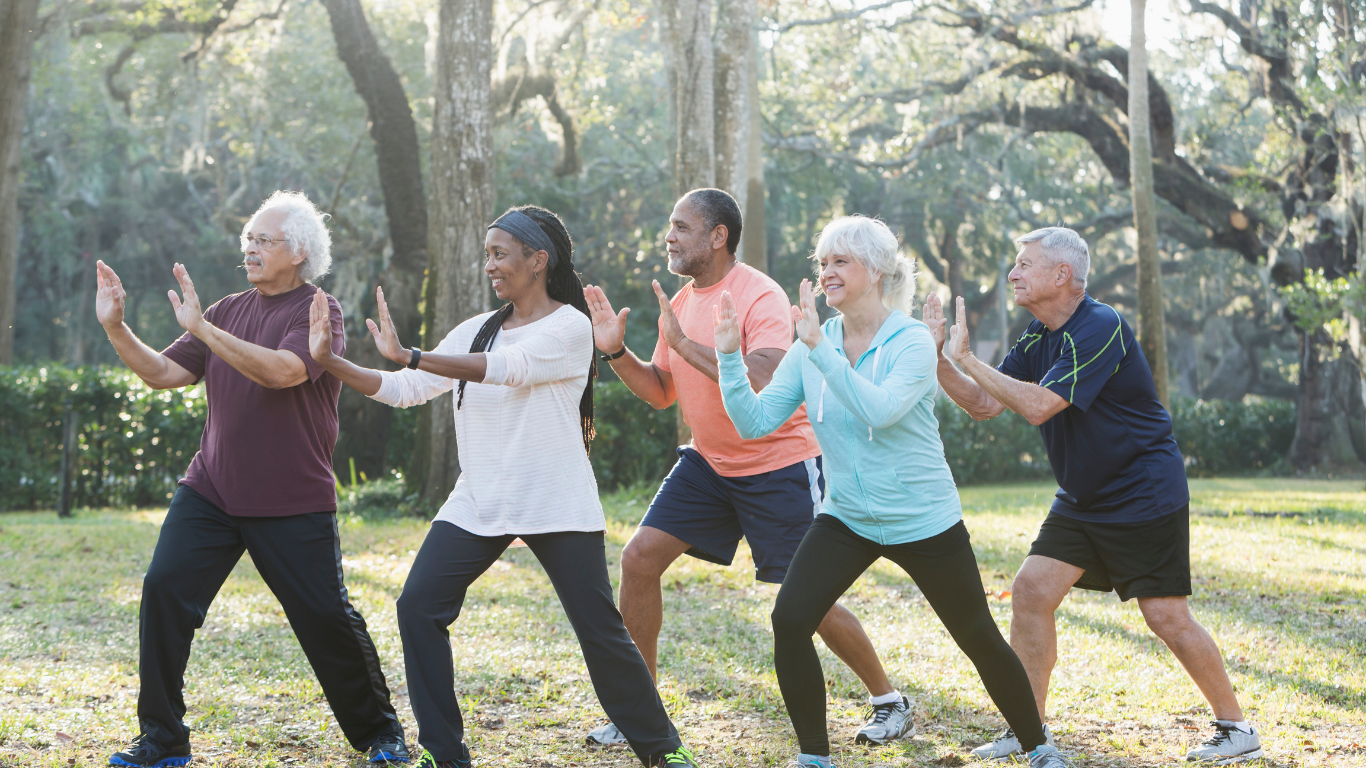 Group of older men and women doing tai chi outdoors 