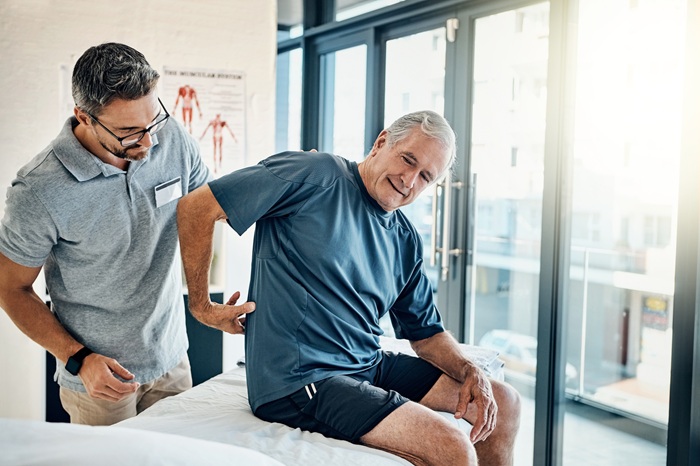 Person experiencing back pain at desk showing signs they need a chiropractor in Asheville NC