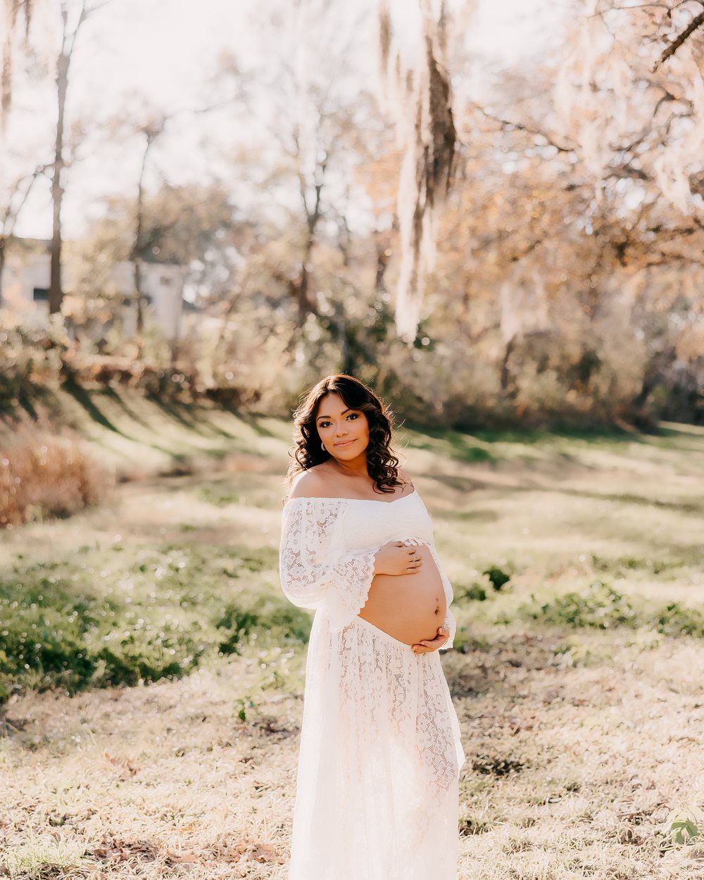 Expectant mother in white lace in a sunlit field