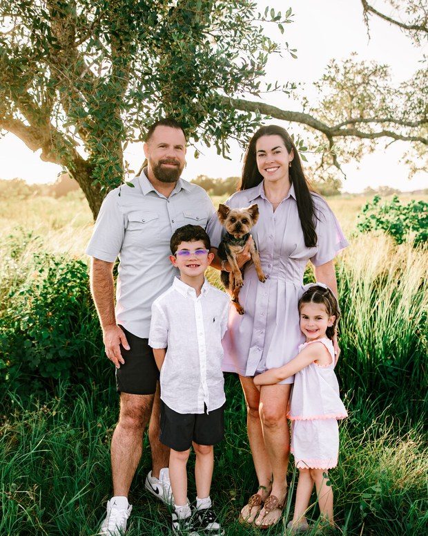 A family standing together in tall green summer grass