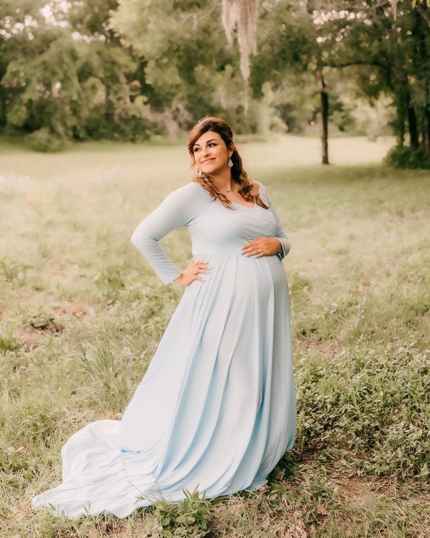 Expectant mother in a white gown outdoors