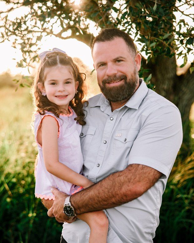 A father holding his young daughter outdoors at golden hour
