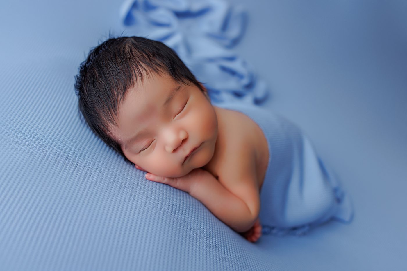 Newborn baby wrapped in blue during a studio session