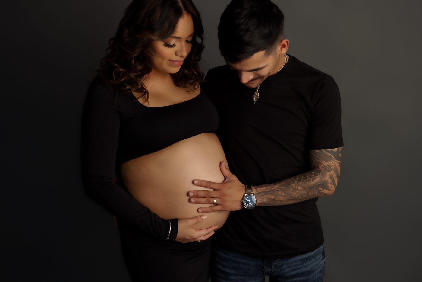 Expecting couple in a dark studio maternity session
