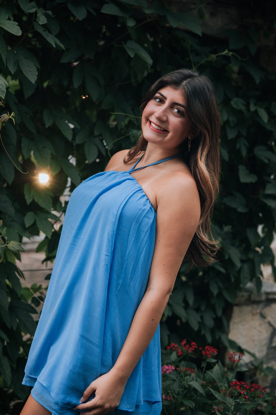 Expecting mother in blue against climbing greenery