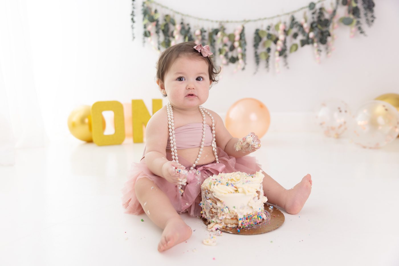 First birthday cake smash with a gold ONE banner