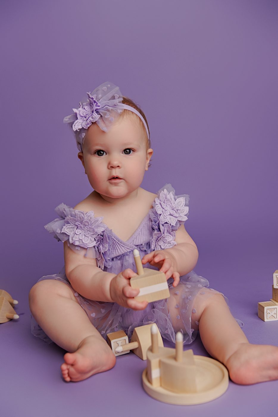 One-year-old girl in purple during her cake smash